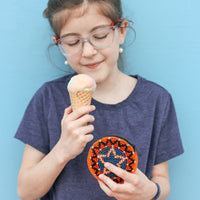girl eats ice cream while holding crocheted coin purse